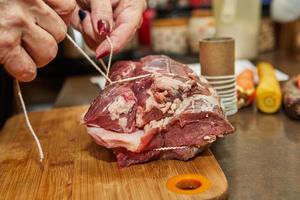 Chef ties the beef with rope and prepares it for baking in the oven photo