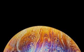 Virtual reality space with abstract multicolor psychedelic planet. Closeup Soap bubble like an alien planet on black background photo