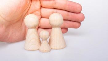 Hand protecting wooden figurines of people as family concept photo