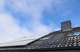 Solar panels with snow on it producing clean energy on a roof of a residential house. photo