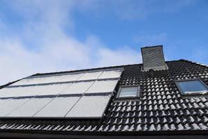 Solar panels with snow on it producing clean energy on a roof of a residential house. photo