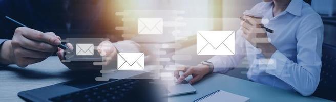 Businessman hands using Laptop typing on keyboard and surfing the internet on office table with email icon, email marketing concept, send e-mail or newsletter, online working internet network. photo