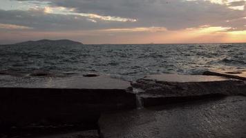 las olas golpean el muelle de hormigón en estambul, distrito de suadiye al atardecer en cámara lenta. el muelle se derrumbó a causa del fuerte oleaje. video