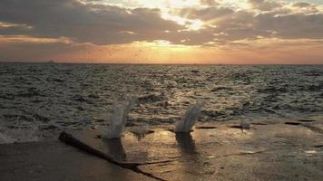 Waves are splashing through inside the holes on the concrete breakwater in Istanbul at the sunset in slow motion video