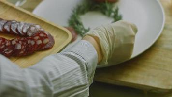 charcutaria plana com salame, diferentes tipos de queijo. tem frutas secas, nozes diversas e mel. arranjo de férias com velas acesas video