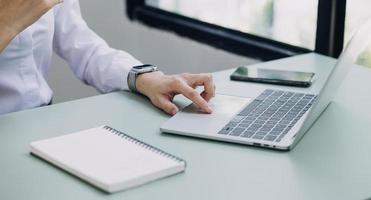 mujer de negocios joven sentada en la oficina en la mesa y usando un teléfono inteligente. en el escritorio hay una computadora portátil y una tableta, en gráficos y gráficos en pantalla. mujer analizando datos. estudiante aprendiendo en línea. foto