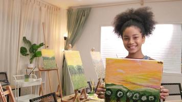 une étudiante noire montre son travail de peinture, fière d'un portfolio, d'une image couleur acrylique sur toile dans une salle de classe d'art et d'un apprentissage créatif avec des compétences de talents à l'école primaire. video
