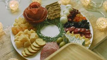 Flat charcuterie with salami, different kinds of cheese. It has dried fruits, various nuts and honey. Holiday arrangement with burning candles video