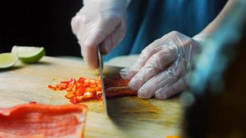 ik houden een zoet rood kapia paprika's besnoeiing in klein stukken. macro het schieten video