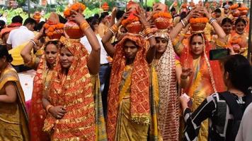 New Delhi, Indien 3 april 2022 - kvinnor med kalash på huvudet under jagannath-templet mangal kalash yatra, indiska hinduistiska hängivna bär jordkrukor som innehåller heligt vatten med en kokosnöt på toppen video