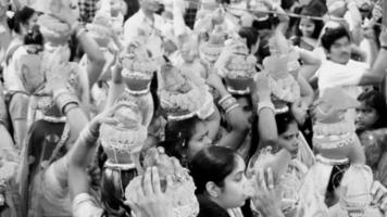 delhi, índia, 03 de abril de 2022 - mulheres com kalash na cabeça durante o templo jagannath mangal kalash yatra, devotos hindus indianos carregam potes de barro contendo água sagrada com coco no topo-preto e branco