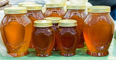 Glass jar of honey set with lid closeup photo