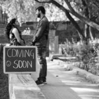 Indian couple posing for maternity baby shoot. The couple is posing in a lawn with green grass and the woman is falunting her baby bump in Lodhi Garden in New Delhi, India - Black and White photo