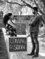 Indian couple posing for maternity baby shoot. The couple is posing in a lawn with green grass and the woman is falunting her baby bump in Lodhi Garden in New Delhi, India - Black and White photo