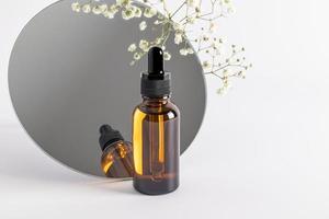 amber cosmetic bottle with a pipette on the background of a round mirror, product packaging, anti-aging serum with peptides, cosmetics layout. photo