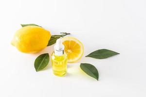 cosmetic lemon oil or whey with vitamin C on a white background with yellow lemon and fruit leaves. natural components. brightening effect. photo