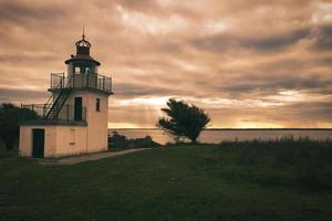 Lighthouse, Spodsbjerg Fyr in Huntsted on the coast of Denmark. Sun rays shining photo