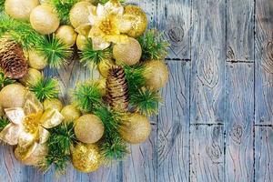 Shiny yellow Christmas balls and cone with barks and pine branches on blue grey wooden background. New year card photo