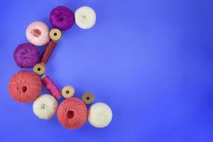 Crescent Moon Multicolored balls and bobbins of woolen yarn, sleeves of wooden thread on blue background. White, purple, pink skeins. Needlework, handmade. view from above. Copy space photo