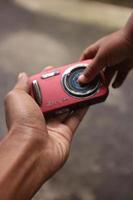 magelang, indonesia, 2022-mano sujetando una cámara de bolsillo roja foto