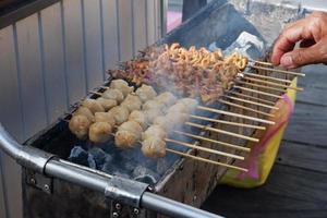 selective focus on chicken intestine satay and grilled meatballs skewered using bamboo and sold at culinary festivals. grilled over wood charcoal photo