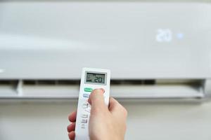 Hand adjusting temperature on air conditioner photo