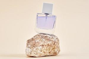 botella de perfume en el podio de piedra con fondo beige foto
