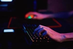 Gamer play computer game, use rgb neon colored keyboard photo