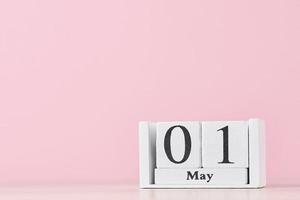 calendario de bloques de madera con fecha 1 de mayo sobre fondo rosa foto