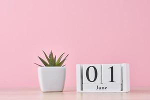 Wooden block calendar with date June 1 on pink background photo