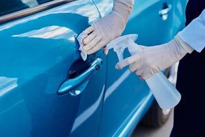 Woman disinfects a car door handle with an antibacterial spray. Car washing photo