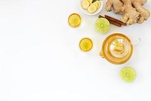 Top view of a cup of tea with ginger root, lime, cinnamon and teapot on white background. Health drink concept. photo