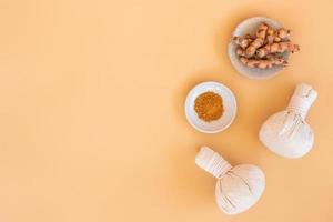 Top view of herbal compress ball with Thai herbal and turmeric on orange pastel background. Spa background concept. photo