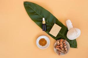 Top view of herbal compress ball with Thai herbal, turmeric, essential oil and bar soap on orange pastel background. Spa background concept. photo