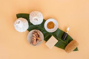 Top view of herbal compress ball with Thai herbal, turmeric, essential oil and bar soap on orange pastel background. Spa background concept. photo