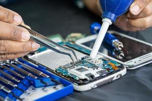 Technician repairing inside of mobile phone by soldering iron. Integrated Circuit. the concept of data, hardware, technology. photo