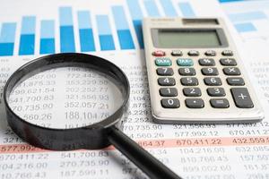 Magnifying glass on charts graphs spreadsheet paper with calculator. Financial development, Banking Account, Statistics, Investment Analytic research data economy. photo