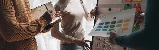 Close up ux developer and ui designer brainstorming about mobile app interface wireframe design on table with customer breif and color code at modern office.Creative digital development agency photo