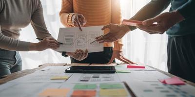 Close up ux developer and ui designer brainstorming about mobile app interface wireframe design on table with customer breif and color code at modern office.Creative digital development agency photo