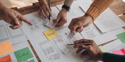 Close up ux developer and ui designer brainstorming about mobile app interface wireframe design on table with customer breif and color code at modern office.Creative digital development agency photo