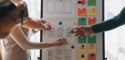 Close up ux developer and ui designer brainstorming about mobile app interface wireframe design on table with customer breif and color code at modern office.Creative digital development agency photo