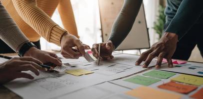 Close up ux developer and ui designer brainstorming about mobile app interface wireframe design on table with customer breif and color code at modern office.Creative digital development agency photo