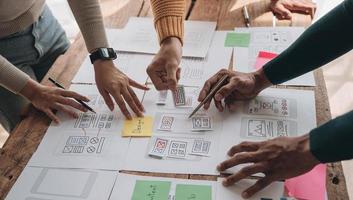 Close up ux developer and ui designer brainstorming about mobile app interface wireframe design on table with customer breif and color code at modern office.Creative digital development agency photo
