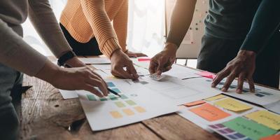 Close up ux developer and ui designer brainstorming about mobile app interface wireframe design on table with customer breif and color code at modern office.Creative digital development agency photo