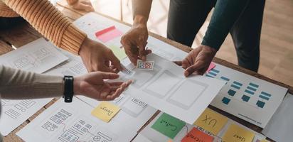 Close up ux developer and ui designer brainstorming about mobile app interface wireframe design on table with customer breif and color code at modern office.Creative digital development agency photo
