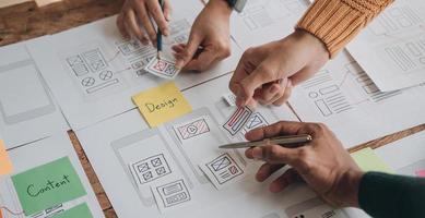 Close up ux developer and ui designer brainstorming about mobile app interface wireframe design on table with customer breif and color code at modern office.Creative digital development agency photo