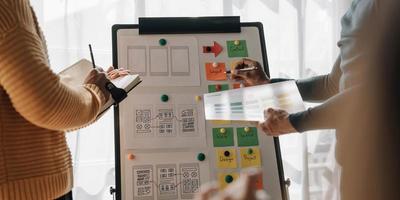 Close up ux developer and ui designer brainstorming about mobile app interface wireframe design on table with customer breif and color code at modern office.Creative digital development agency photo