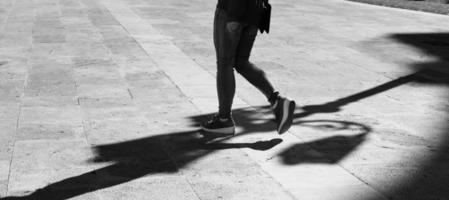 Girl walking with elongated shadow in black and white.Black and white. Shadow and light, girl silhouette photo