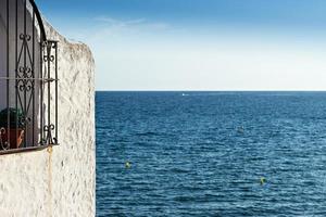 Window with pots and wrought iron fence overlooking the sea. Horizontal image. photo