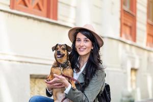 young attractive woman playing with her dog on the city street, lifestyle people concept. Beauty woman with her dog playing outdoors photo